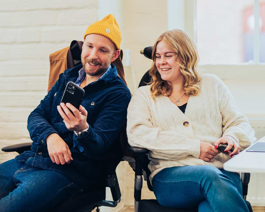 Två personer tittar glad på en telefon