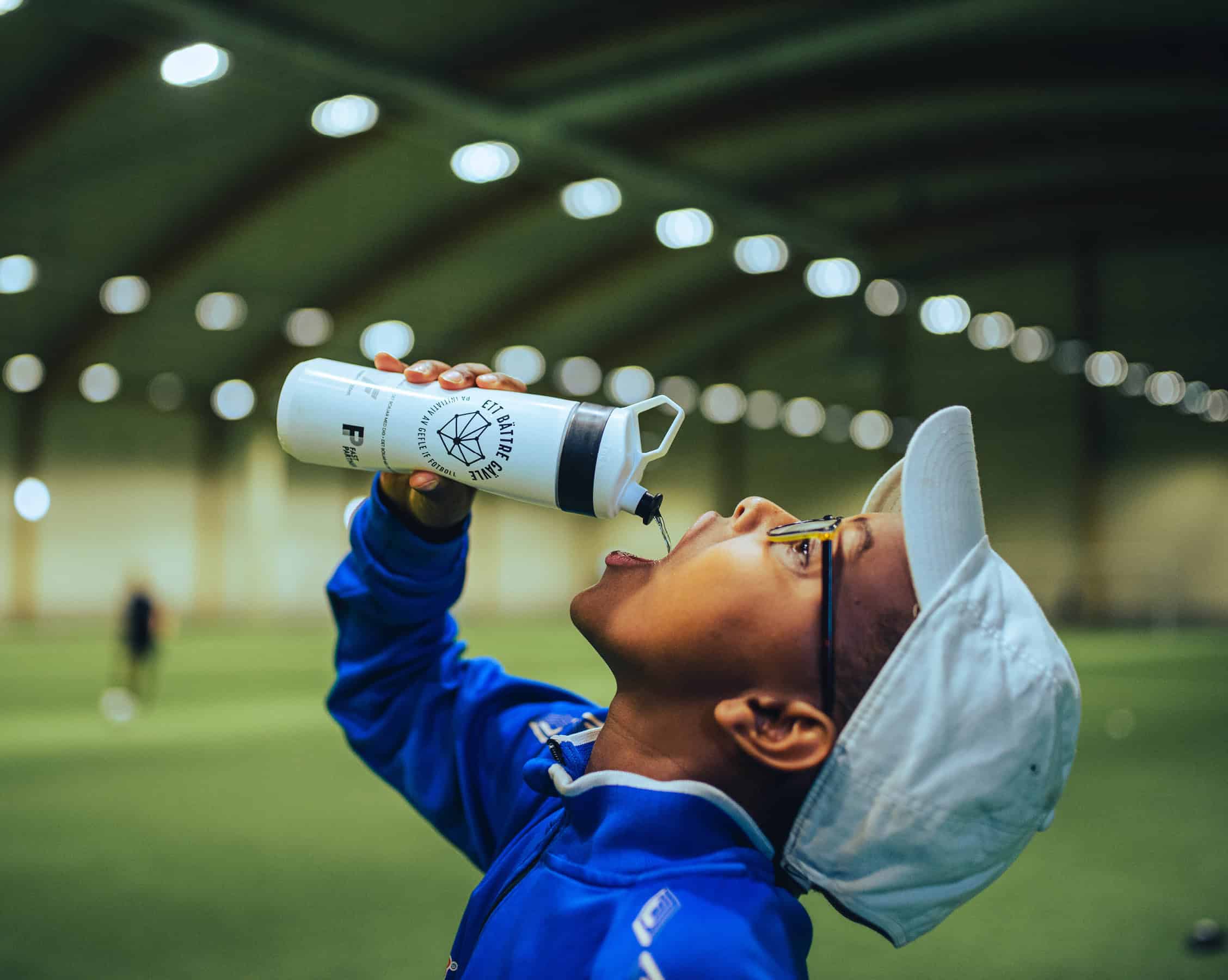 Ung fotbollskille dricker ur vattenflaska