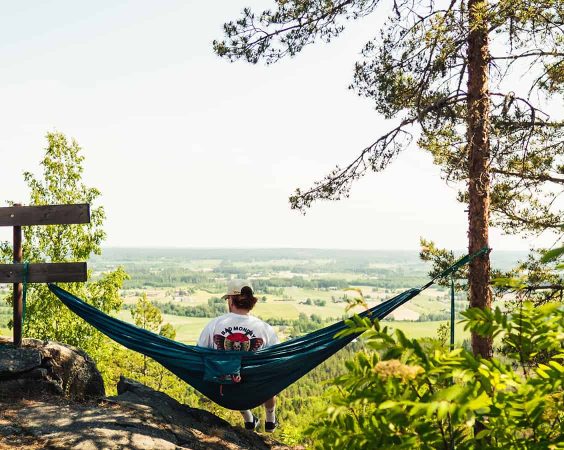 Kille sitter i en hängmatta och tittar ut över ett landskap