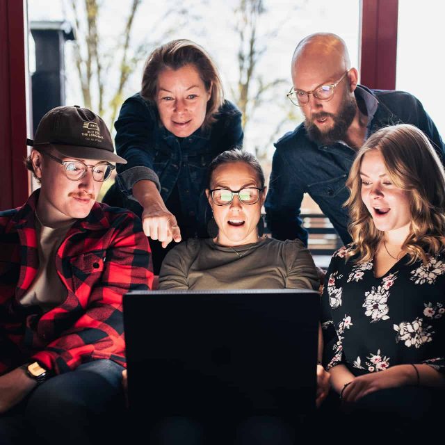 Fem personer tittar tillsammans mot en laptopskärm